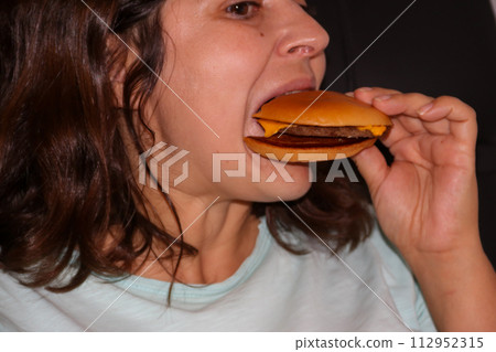 Caucasian woman eating tasty cheeseburger 112952315