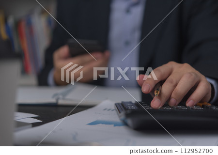 Businessman using calculator and accounting documents at desk with laptop computer.. 112952700