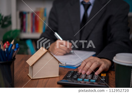 real estate agent with house. Business person holding pen sign a contract approved on mortgage loan contract agreement document house plan on the table. real estate agent with house. Business person holding pen sign a contract approved on mortgage loan contract agreement document house plan on the table. 112952720