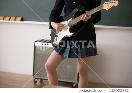 Student playing guitar. Image of brass band or club activities. Easy to use without face. Close-up of hands. Student playing guitar. Image of brass band or club activities. Easy to use without face. Close-up of hands. 112952882