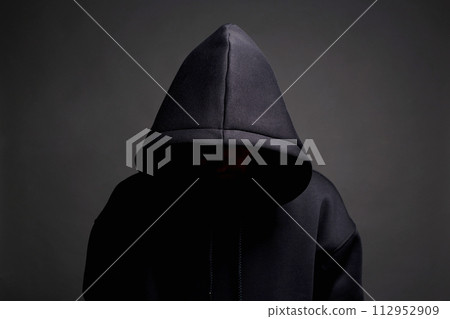 Man in Black Hood posing in dark studio. Boy in a hooded sweatshirt Man in Black Hood posing in dark studio. Boy in a hooded sweatshirt 112952909