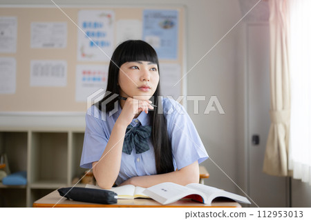 高中女生在教室裡學習的短袖。因學習困難而憂心忡忡、思考的形象。 高中女生在教室裡學習的短袖。因學習困難而憂心忡忡、思考的形象。 112953013