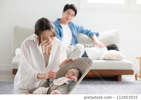 一個亞洲（日本）四口之家在客廳裡撫養孩子。嬰兒和母親互相看著對方。 112953035