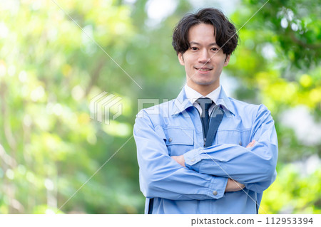 Man in work clothes, outdoors, fresh greenery, arms folded 112953394