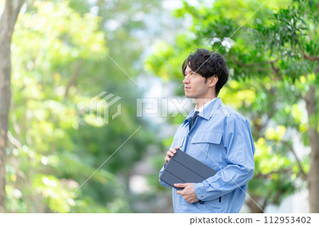 穿著工作服的男人在戶外新鮮的綠色平板電腦 穿著工作服的男人在戶外新鮮的綠色平板電腦 112953402