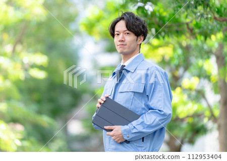 穿著工作服的男人在戶外新鮮的綠色平板電腦 112953404