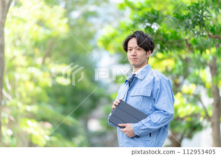 穿著工作服的男人在戶外新鮮的綠色平板電腦 112953405