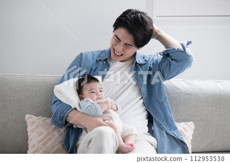 A young father on holiday taking care of a baby in the living room. Good luck! daddy 112953538