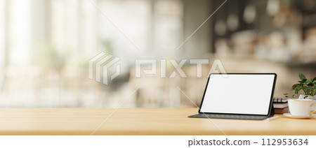 A tablet mockup with a wireless keyboard on a wooden table in a cosy, minimalist coffee shop. A tablet mockup with a wireless keyboard on a wooden table in a cosy, minimalist coffee shop. 112953634