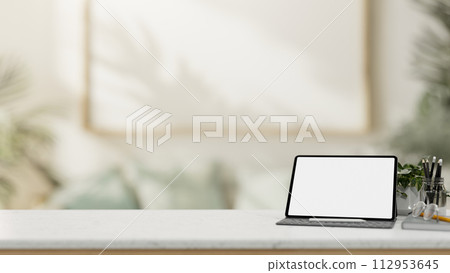 A white-screen digital tablet mockup on a white tabletop in a modern living room. A white-screen digital tablet mockup on a white tabletop in a modern living room. 112953645