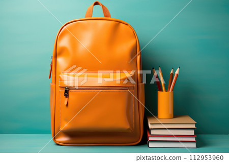 New school bag. A large orange backpack standing on the table and writing materials. Back to School concept New school bag. A large orange backpack standing on the table and writing materials. Back to School concept 112953960