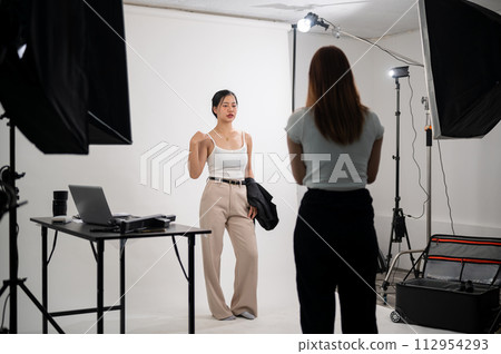 A professional photographer is taking pictures of an attractive young Asian female model in a studio 112954293