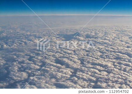 Mt. Fuji emerging from a sea of clouds seen from an airplane 112954702