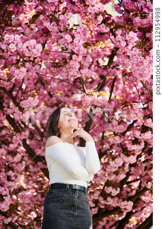 Woman allergic enjoying after treatment from seasonal allergy at spring. Portrait of happy beautiful woman smiling in front of blooming sakura tree at springtime. Spring allergy concept. Woman allergic enjoying after treatment from seasonal allergy at spring. Portrait of happy beautiful woman smiling in front of blooming sakura tree at springtime. Spring allergy concept. 112954998
