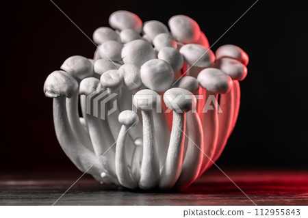 Closeup of a bunch of shimeji mushrooms with red light, on wooden and black background, with selective focus, shimiji mushrooms, superfood, a type of delicious oyster mushroom, healthy food 112955843