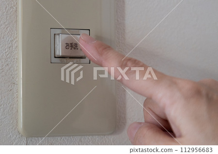 Hand touching the light switch in the bathroom Hand touching the light switch in the bathroom 112956683