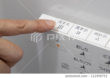 Hand operating the toilet wall remote control 112956752