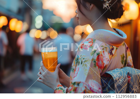 Young woman in kimono drinking beer in the night city 112956883
