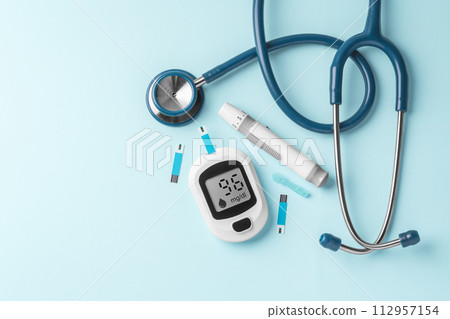 Blood glucose meter, lancet and stethoscope on blue background, diabetes concept, top view, copy space 112957154