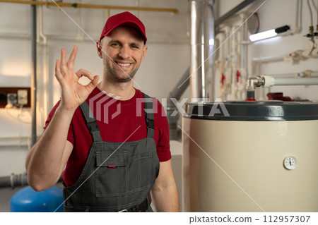 Professional Plumber Inspects Water Heater in Residential Basement 112957307