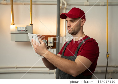 Professional Technician Inspecting Heating System in Residential Basement During Winter Professional Technician Inspecting Heating System in Residential Basement During Winter 112957359
