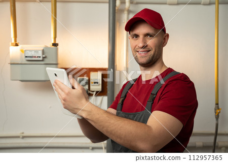 Professional Technician Inspecting Heating System in Residential Basement During Winter 112957365
