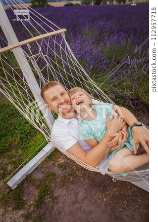 father and daughter lie in a hammock. lavender field in the background 112957718