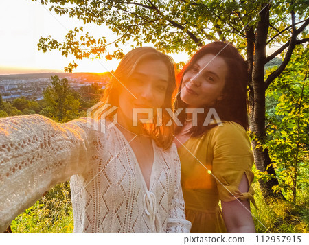 two pretty women take a selfie at sunset two pretty women take a selfie at sunset 112957915