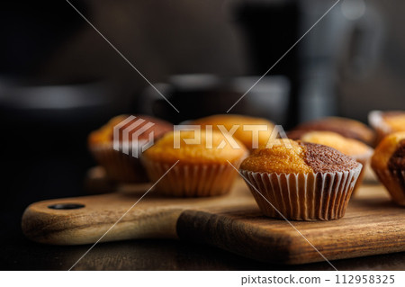 Close Up of a Muffins on cutting board on black table. Close Up of a Muffins on cutting board on black table. 112958325
