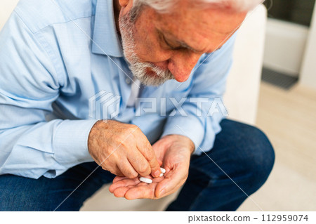 Middle aged senior man holding medical pills. Mature old senior grandfather taking medication cure pills vitamin. Age prescription medicine healthcare therapy concept 112959074