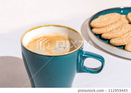 Fresh Coffee in a Blue Mug Beside Crispy Cookies on a Sunny Day Fresh Coffee in a Blue Mug Beside Crispy Cookies on a Sunny Day 112959485