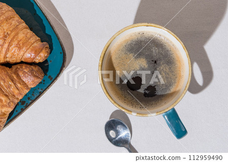 Top view of Morning Coffee and Fresh Croissants on a Textured Background 112959490