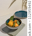 Fresh Tangerines in a Bowl on Table With Sunlight and Shadow Play 112959492