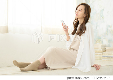 A woman sitting and watching a smartphone A woman sitting and watching a smartphone 112959528