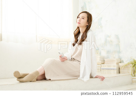A woman sitting and watching a smartphone A woman sitting and watching a smartphone 112959545