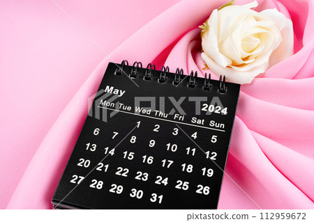 May 2024 desk calendar black color and rose on pink textile. 112959672