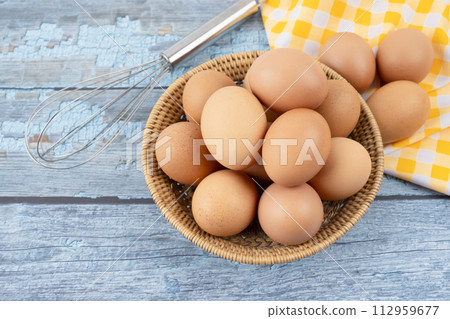 Raw chicken eggs in wooden basket. 112959677