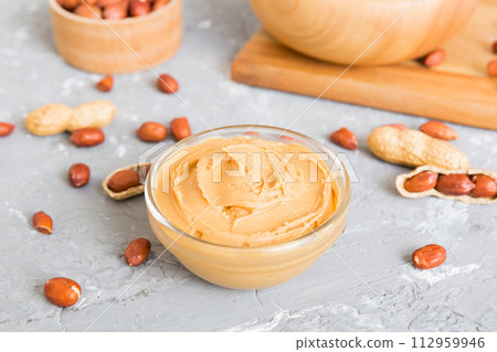 Bowl of peanut butter and peanuts on table background. top view with copy space. Creamy peanut pasta in small bowl Bowl of peanut butter and peanuts on table background. top view with copy space. Creamy peanut pasta in small bowl 112959946