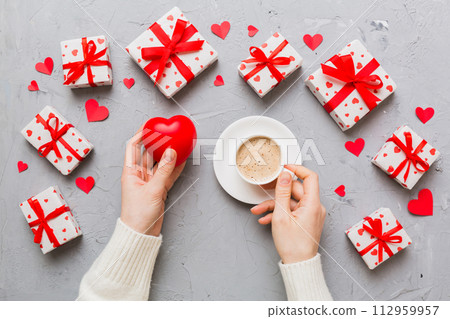 Flat lay of heart shaped cup of black coffee in the hands of women on colored background with copy space top view. Valentine day and holiday concept 112959957