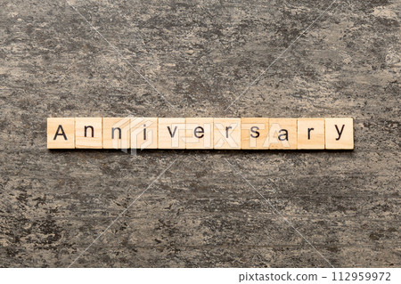 anniversary word written on wood block. anniversary text on cement table for your desing, concept 112959972