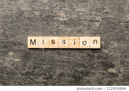 MISSION word written on wood block. MISSION text on table, concept 112959994