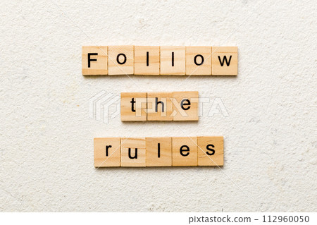 Follow The Rules word written on wood block. Follow The Rules text on table, concept 112960050