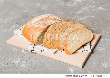Assortment of freshly sliced baked bread with napkin on rustic table top view. Healthy unleavened bread. French bread slice Assortment of freshly sliced baked bread with napkin on rustic table top view. Healthy unleavened bread. French bread slice 112960365