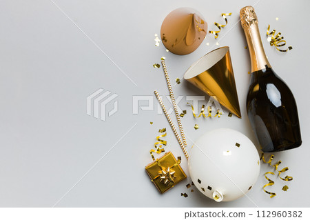 Flat lay composition of Champagne bottle gift box ribbons and confetti on colored background. Flat lay, top view holiday concept 112960382