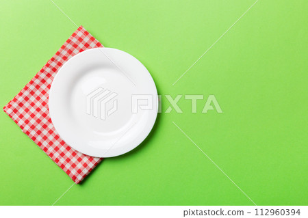 Top view on colored background empty round white plate on tablecloth for food. Empty dish on napkin with space for your design 112960394