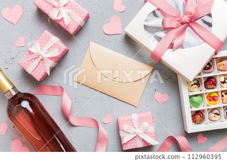 top view photo of st valentine day decor shopping, bag, wine, bottle, envelope, gift, box, candy and red heart on colored background with empty space. Frame background 112960395