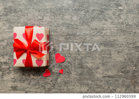 Top view photo of valentine day decorations gift box with red ribbon bow on colored background. Holiday gift boxes with top view Top view photo of valentine day decorations gift box with red ribbon bow on colored background. Holiday gift boxes with top view 112960399