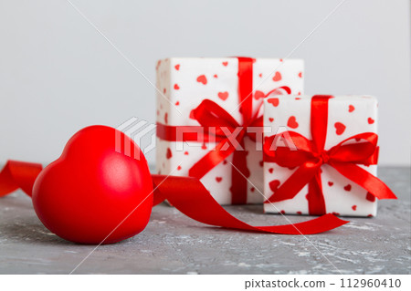 gift box with red bow and red heart on colored background. Perspective view. Flat lay 112960410