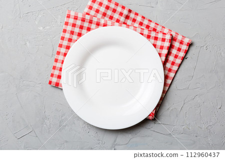 Top view on colored background empty round white plate on tablecloth for food. Empty dish on napkin with space for your design Top view on colored background empty round white plate on tablecloth for food. Empty dish on napkin with space for your design 112960437
