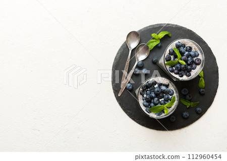 Healthy breakfast or morning with chia seeds vanilla pudding and blueberry berries on table background, vegetarian food, diet and health concept. Chia pudding with coconut milk and blueberry 112960454